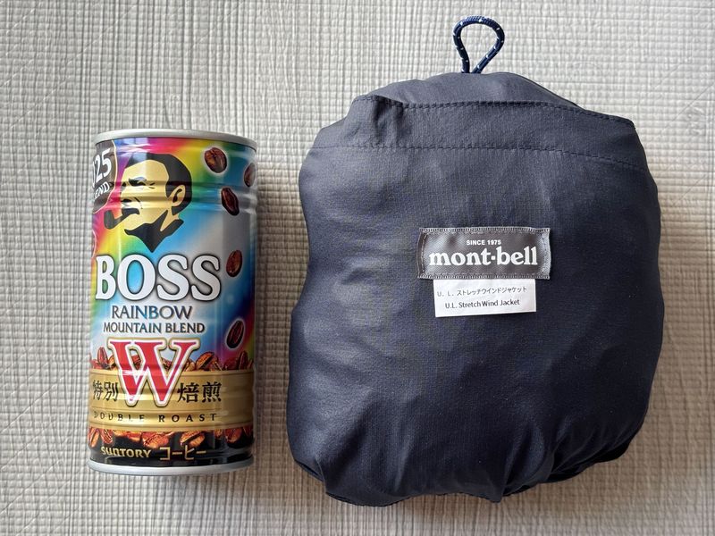 モンベル U.L.ストレッチ ウインドジャケットを左ポケット裏に収納した状態。缶コーヒーとのサイズ比較。