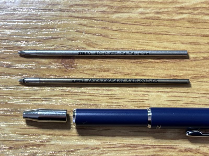 ZEBRA SL-F1 miniの純正4C-0.7芯とJETSTREAM SXR-200-05芯の比較写真。換装中の本体も写っており、リフィルの形状が分かる構図。